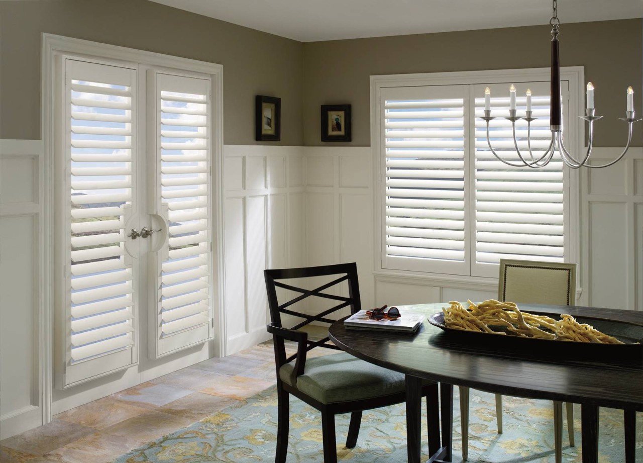 Home dining room with windows and French doors outfitted with Hunter Douglas Palm Beach™ Polysatin™ Vinyl Shutters at Wessco Blinds near Seattle, WA