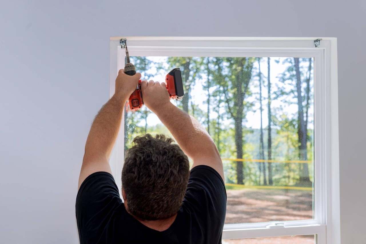 Professional window treatment installer drilling fasteners to a window frame for new blinds or shades at Wessco Blinds near Seattle, WA